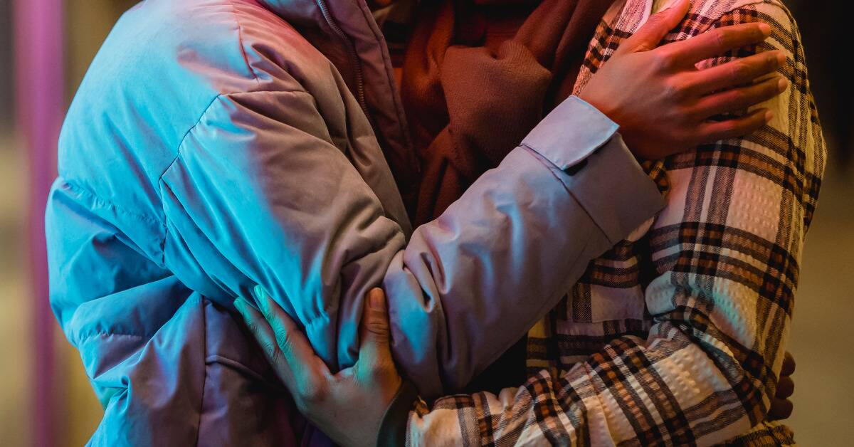 Two people in winter coats hugging.