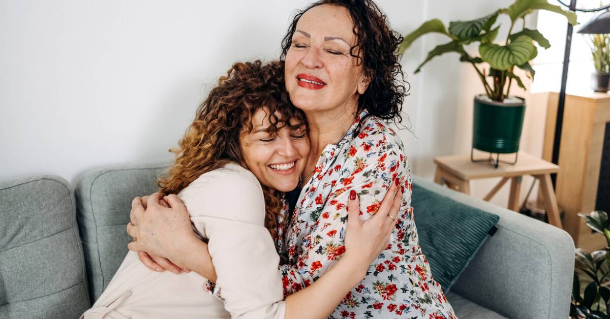A woman and her MIL hugging while smiling.