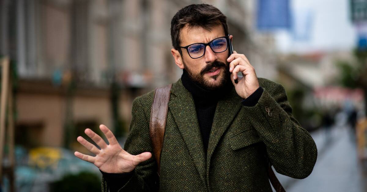 A man on the phone, gesturing with his hand as he speaks, seeming confused or stern.