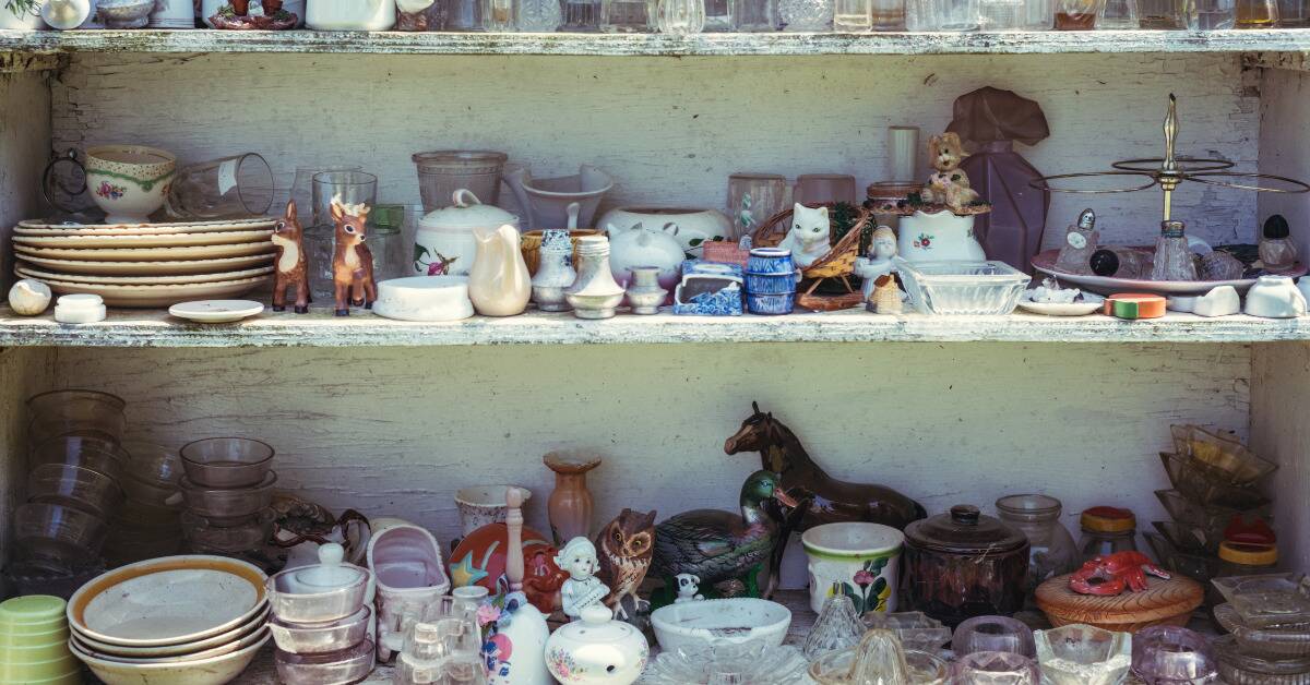 Long, white, worn shelves covered in small dishes, knick knacks, and other delicate decor items.