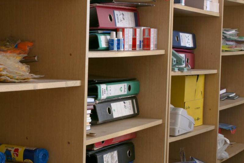 An angled shot of a wall shelving unit, every shelf full of binders and other office suplies.