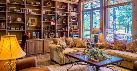A family living room with a very large shelving unit in the back, every shelf full of stuff.