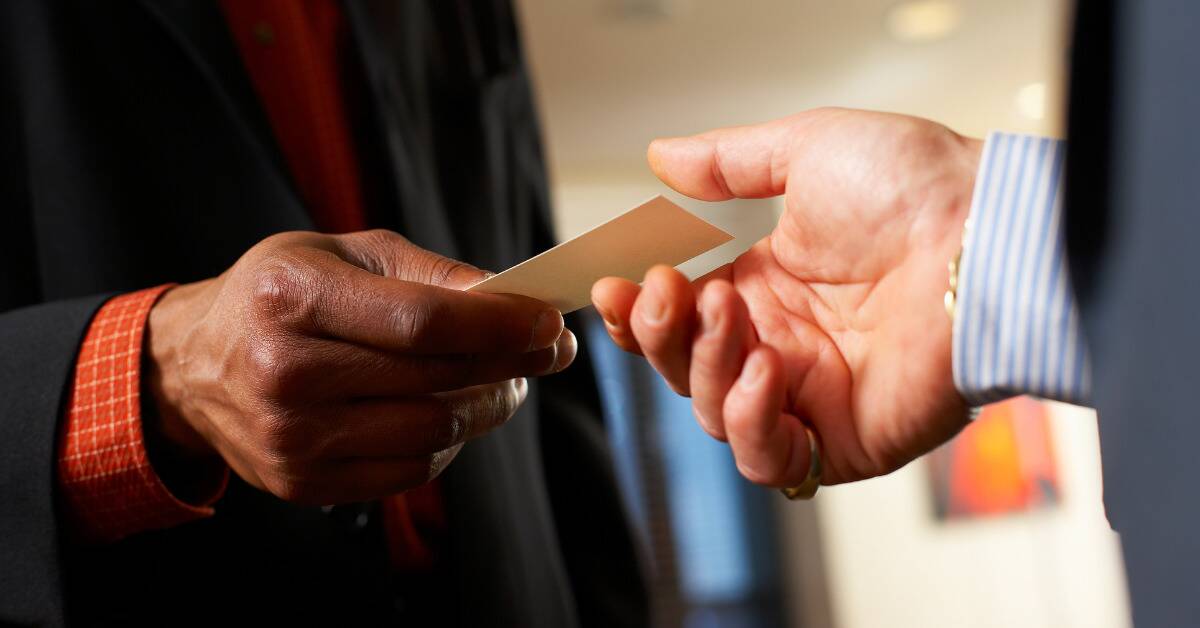 A close shot of two men exchanging business cards at a networking event.