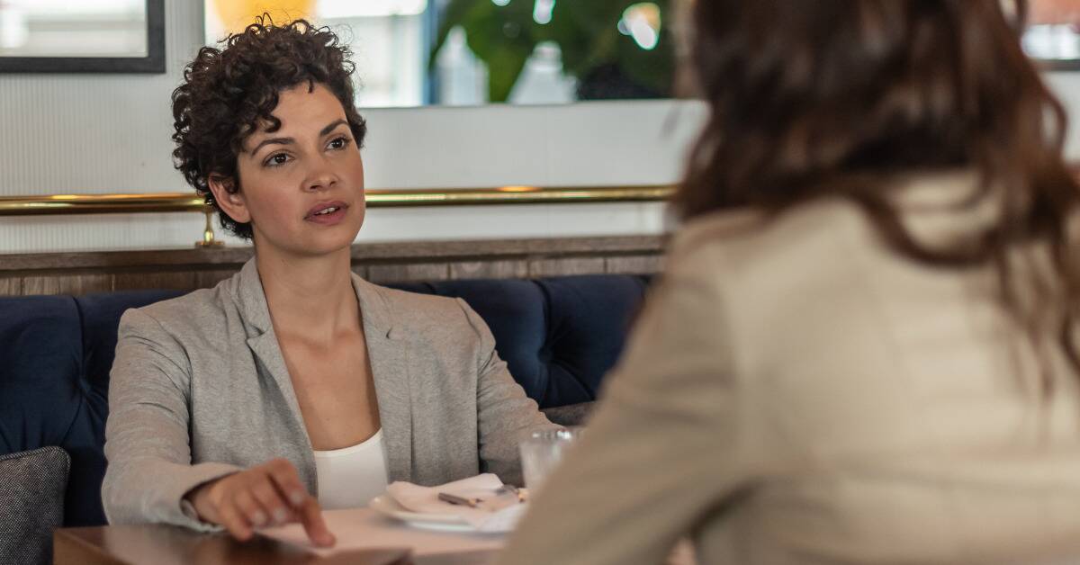 Two women at a table, seemingly in a serious conversation.