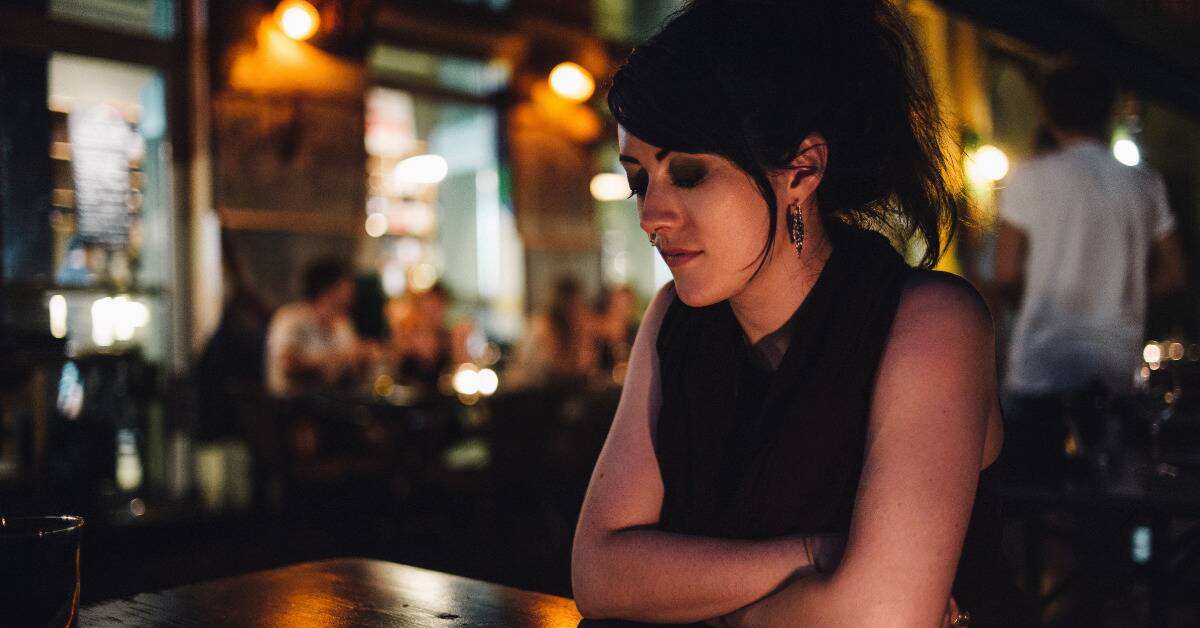 A woman sitting at a bar looking forlorn and sad
