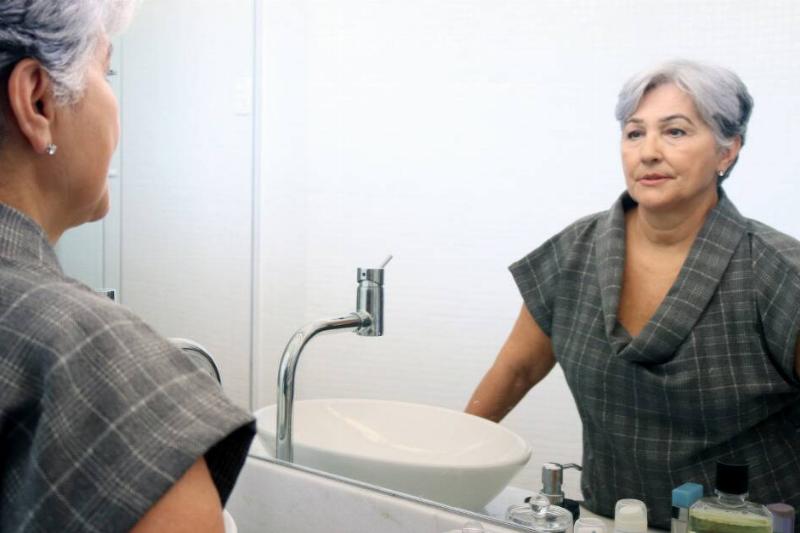 A woman lookin at herself in a bathroom mirror.