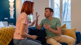 A couple yelling at each other while sitting on a couch.