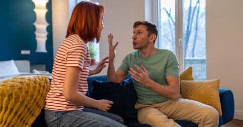 A couple yelling at each other while sitting on a couch.