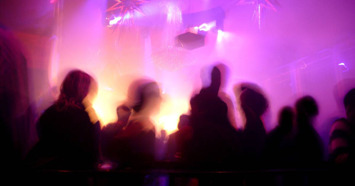 A blurry, long exposure shot of people walking about a night club.