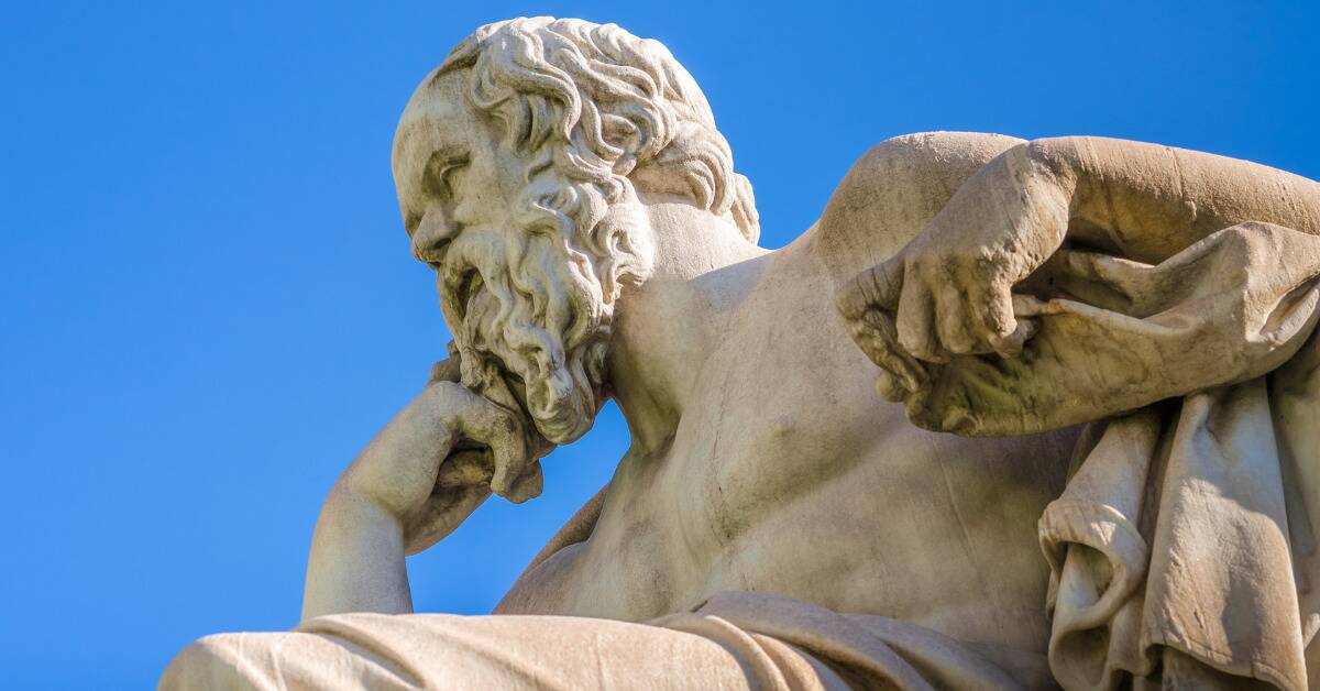 A philosopher's statue against a bright blue sky.