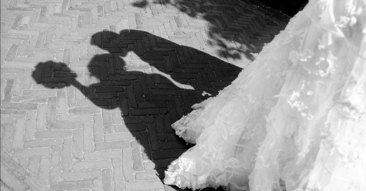 The shadows of a married couple kissing, the bride's dress train visible.