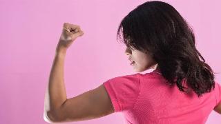 A woman flexing the muscles in her left arm, looking in profile view at her own bicep.