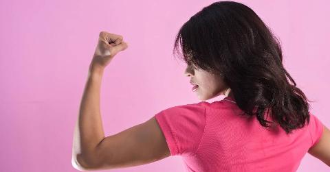A woman flexing the muscles in her left arm, looking in profile view at her own bicep.