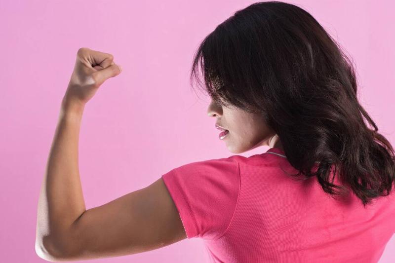 A woman flexing the muscles in her left arm, looking in profile view at her own bicep.