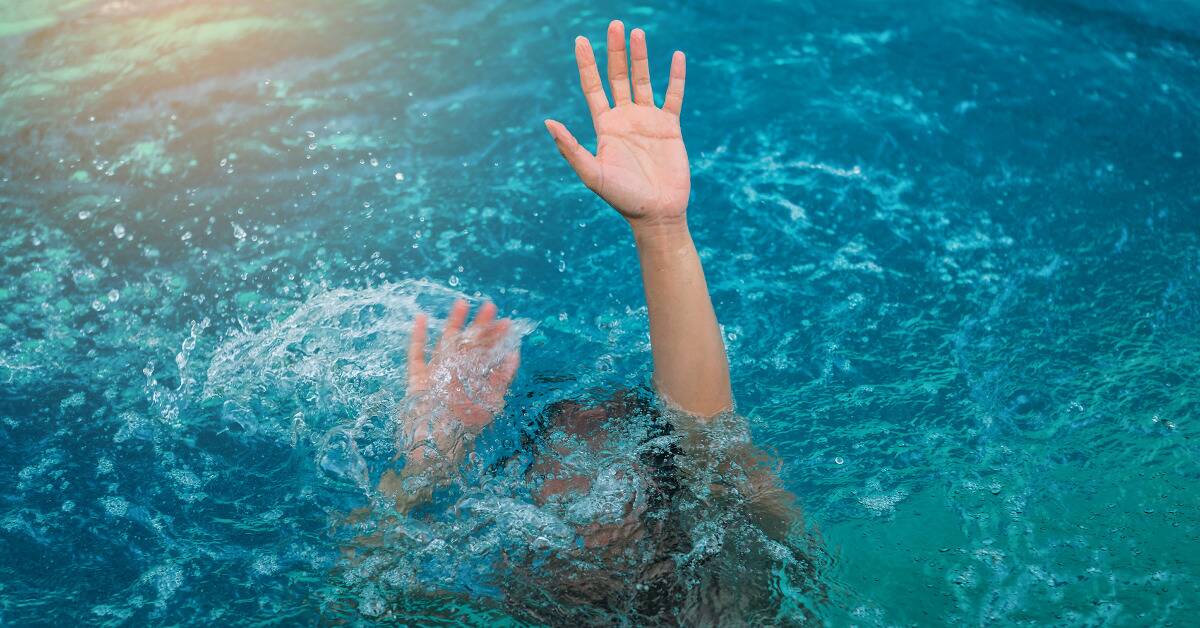 A person's hands reaching up from underwater as they're drowning.