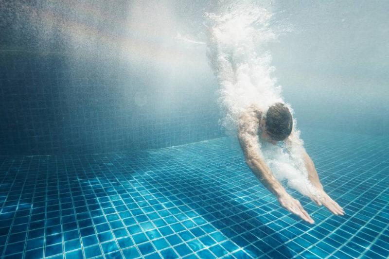 An underwater shot of someone diving into a pool.