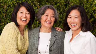Three adult sisters all smiling as they stand for a photo outside.