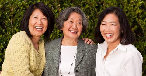 Three adult sisters all smiling as they stand for a photo outside.