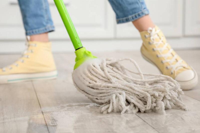 A close shot of a woman in yellow shoes mopping the floor.