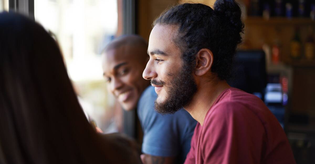 A man sitting out with his friends, smiling peacefully.