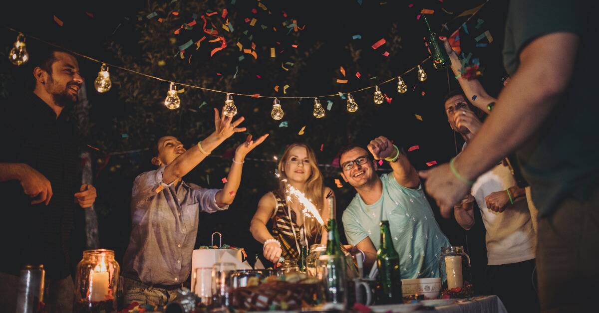 A group of friends having a celebration outside with confetti and sparklers.