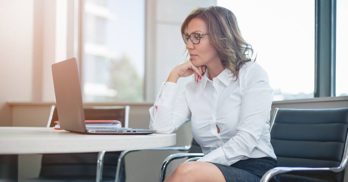 A hardworking business woman looking at her laptop with serious, stern expression.