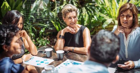 Two women sat at a table outside during a business meeting.