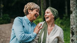 Two women talking and laughing as they walk together outside.
