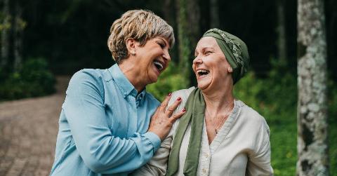 Two women talking and laughing as they walk together outside.