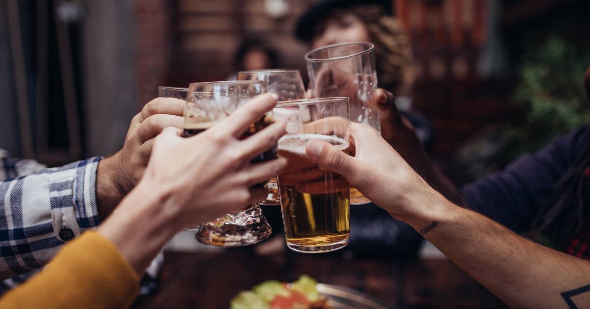 A group of friends cheersing their glasses together at the center of a table.
