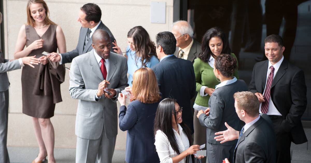A group of business people networking and exchanging business cards with each other.