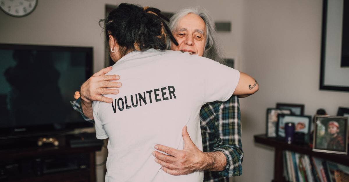 Someone in a shirt marked 'volunteer' hugging someone they presumably just helped.