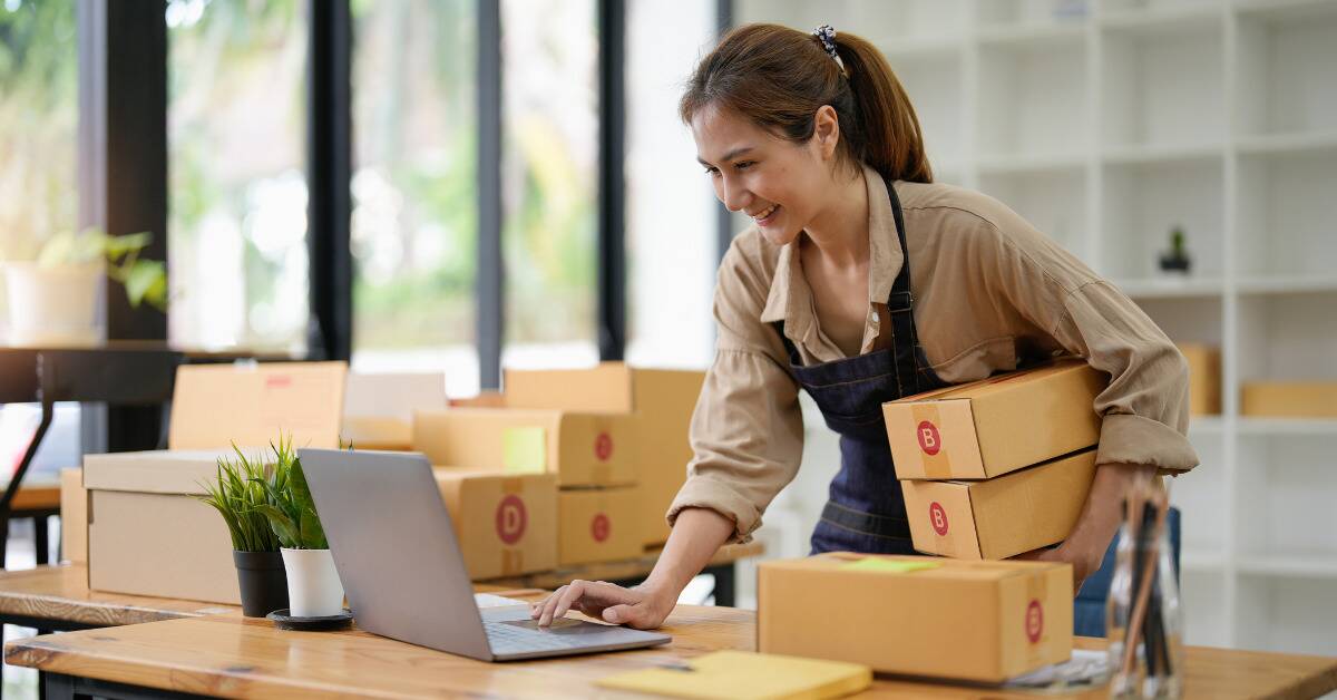 A woman smiling as she packs boxes for her business.