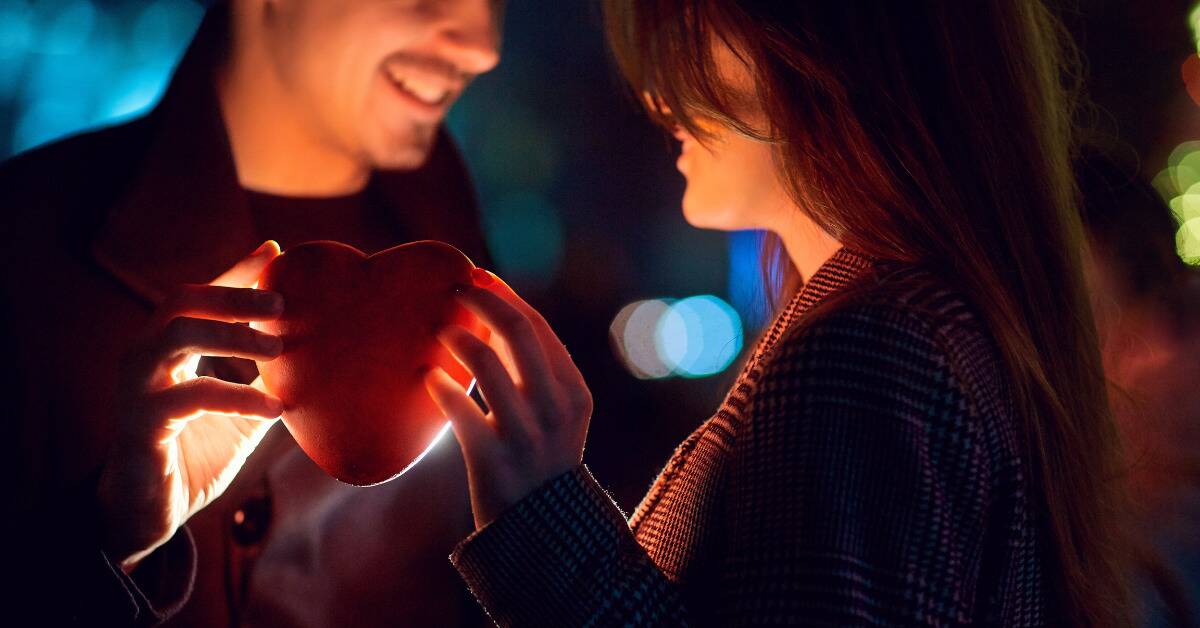 A couple holding a heart between their two hands.