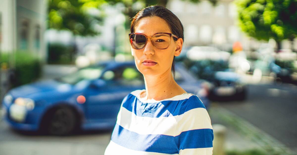 A woman wearing a pair of sunglasses with one of the lenses popped out.