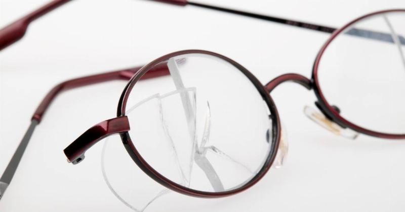 A pair of round glasses with large cracks through one lens.