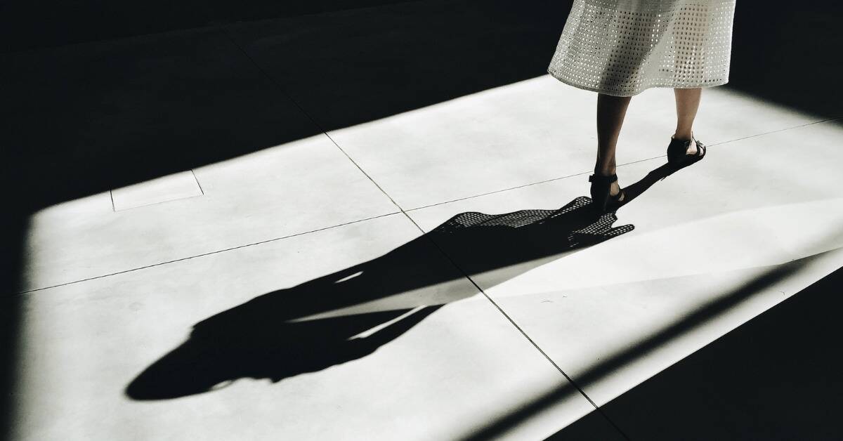 A shot of a woman's legs as she walks away, her shadow stretched out behind her.