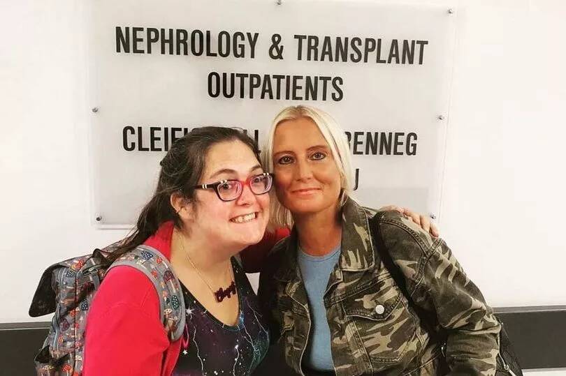 Lucy and Katie standing in front of the Nephrology & Transplants Outpatients division sign.