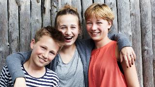 Three siblings all smiling at the camera.