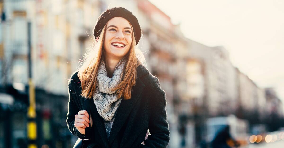 A woman smiling confidently as she walks down the street.