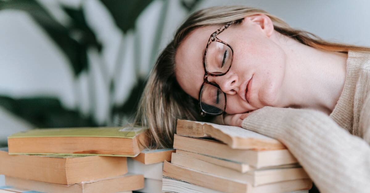 A woman who's fallen asleep on a stack of books.