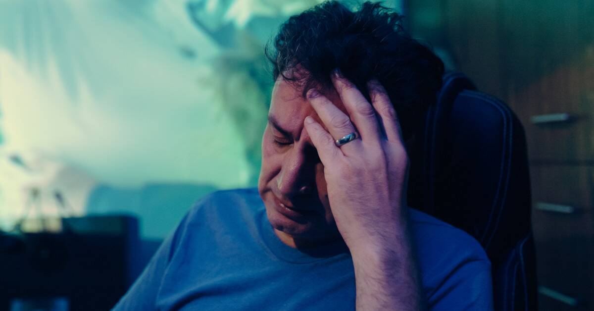 A man leaning his head in his hand, looking sad.