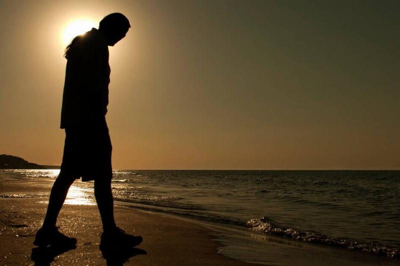 The silhouette of a man walking along the beach.