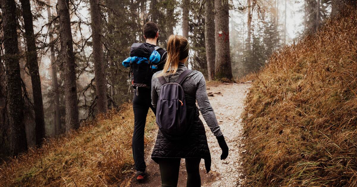 A couple hiking through a forest path.