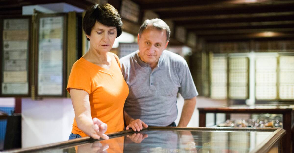 A couple looking at stuff in a display table at a museum.