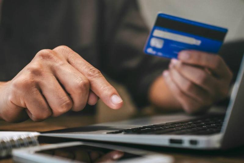 A close shot of someone holing up a credit card in order to buy something online.
