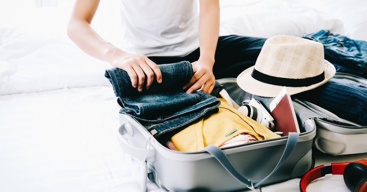 Someone packing a small suitcase with clothes for a vacation.
