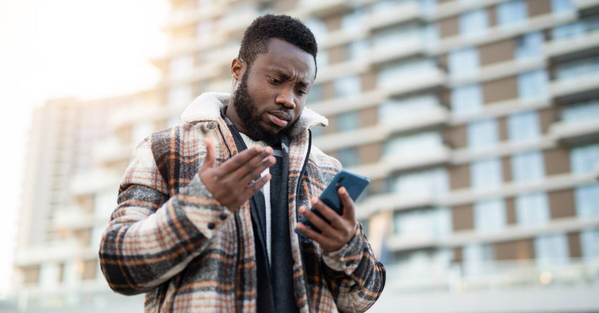 A man looking at his phone with a frustrated expression.