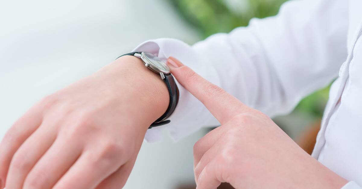 A close shot of a woman tapping the watch on her wrist.