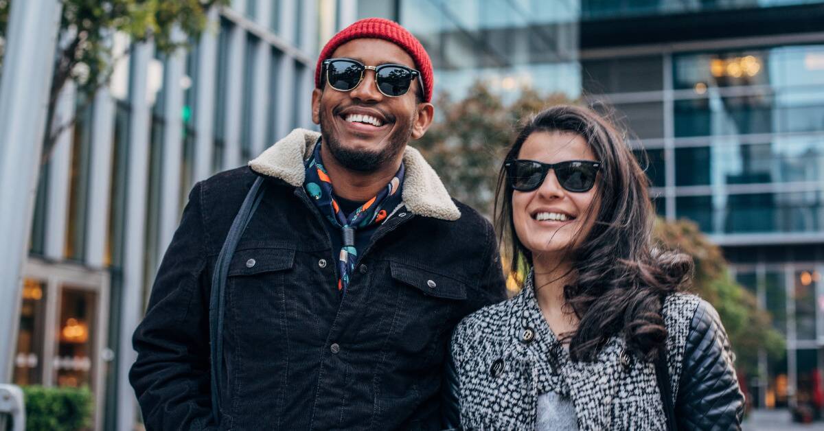 A couple smiling together as they walk down a city street.